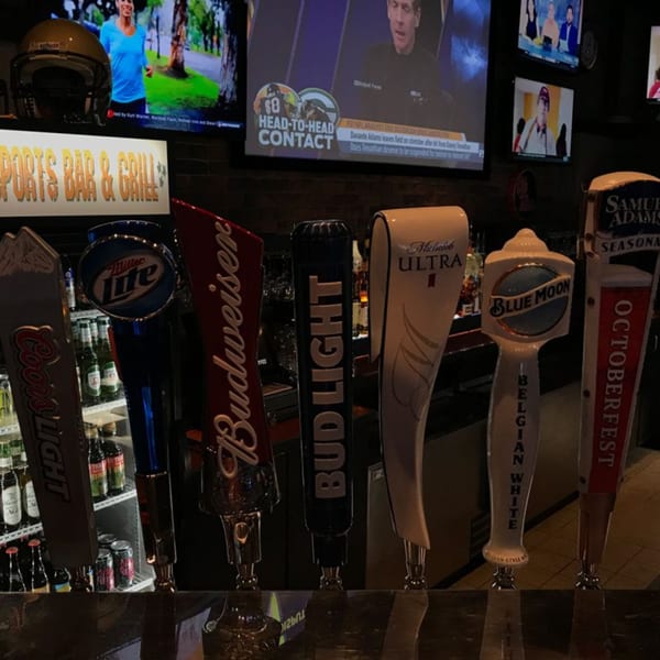 Beer taps from various brands, including Coors Light, Miller Lite, Budweiser, and Blue Moon, at a bar.