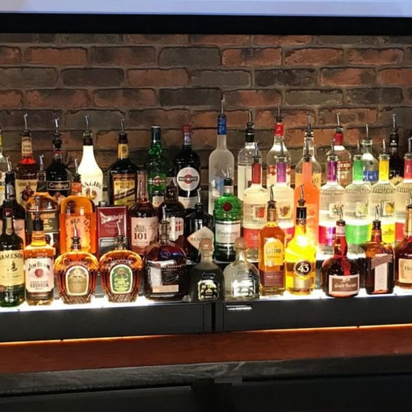 A well-stocked bar at 731 Sports Bar and Grill, featuring numerous liquor bottles against a brick wall.