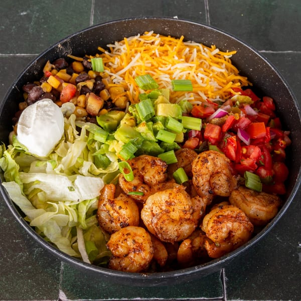 Shrimp bowl with lettuce, sour cream, corn, black beans, avocado, pico de gallo, and shredded cheese.