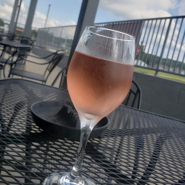 A glass of rosé wine sits on a black mesh outdoor table at 731 Sports Bar and Grill.