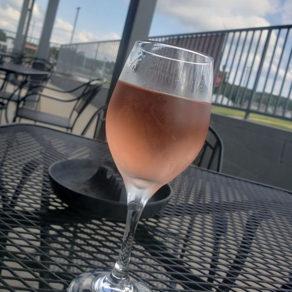 A glass of rosé wine sits on a black mesh outdoor table at 731 Sports Bar and Grill.